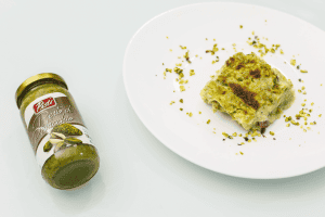 Pistachio cake with pistachio paste on a white plate, pistachio crumbs scattered around.