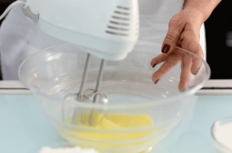 Fornelli per dolci artigianali Hand mixing batter with electric mixer in a glass bowl.