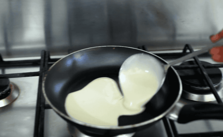 Crema di latte in cottura Cream pouring into a pan.
