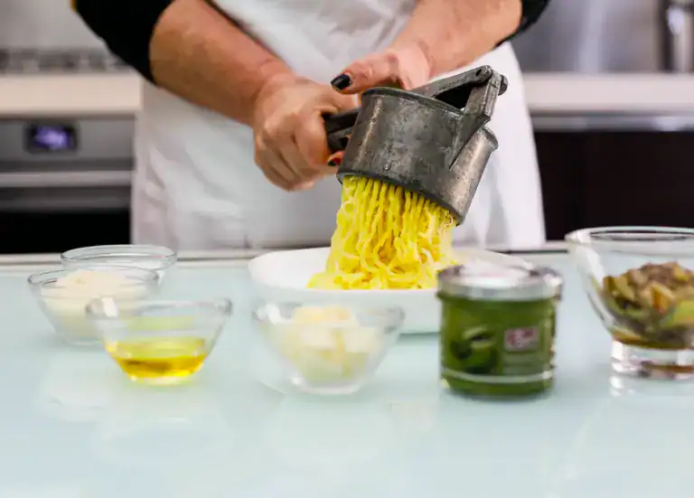 Freshly made artisanal pasta being grated with a manual tool. Handmade pasta being grated with a traditional tool in a professional kitchen.