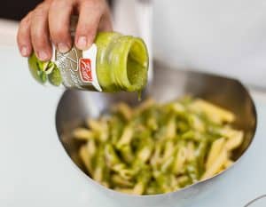 Adding Sicilian-style pesto to pasta in a bowl.