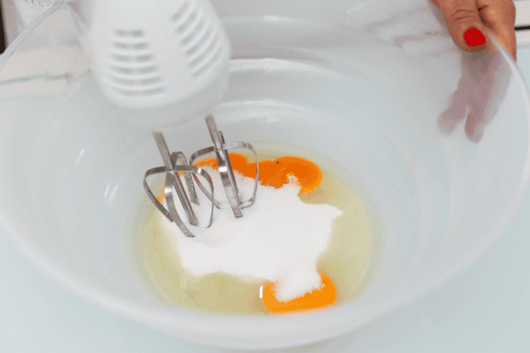 Creamy cake batter with eggs in a mixing bowl. Eggs and sugar being mixed for artisanal Sicilian dessert.
