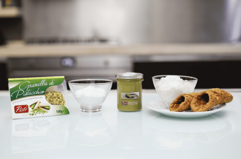 Pistachio Dessert Ingredients Pistachio dessert ingredients including pistachio granella, sugar, and cookies on a white surface.