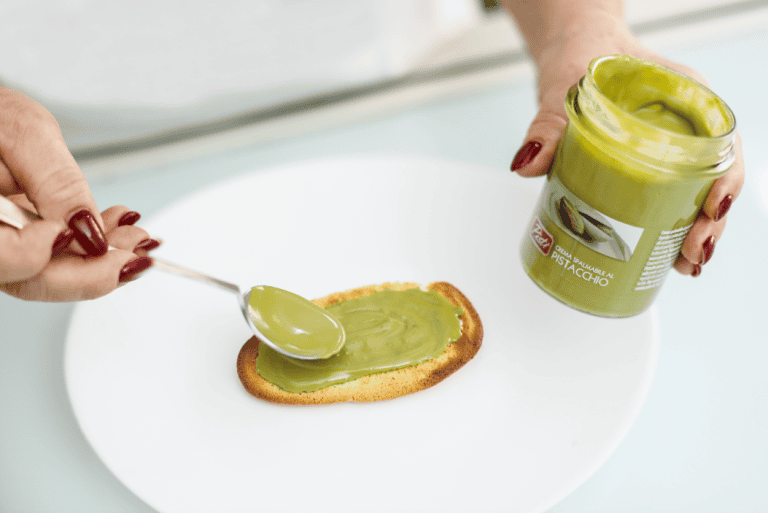 Crema di pistacchio su pane tostato Crema di pistacchio verde spalmata su pane tostato con cucchiaino.
