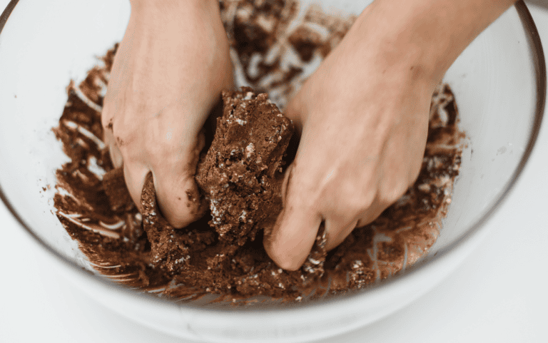 Handmade chocolate dough being kneaded in a bowl Hand kneading rich chocolate dough for artisanal sweets.