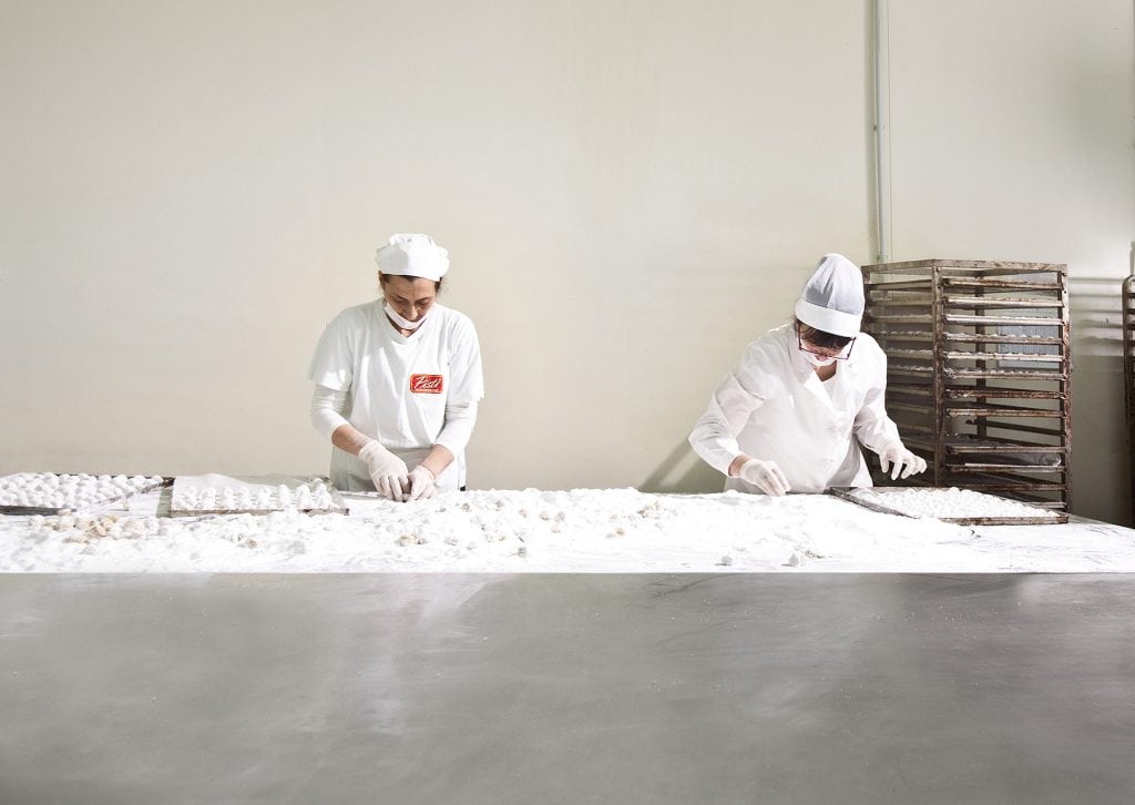 Artisans preparing traditional Sicilian sweets by hand in a clean, professional kitchen.