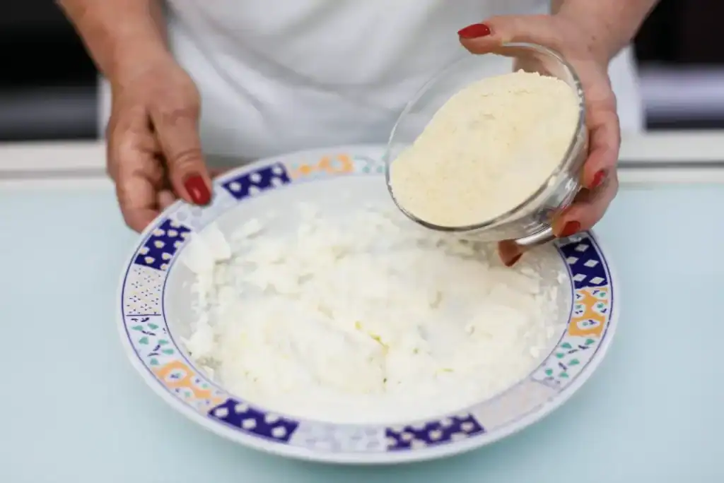 Pistì Sicilian Artisanal Ricotta Cheese Hand pouring fresh ricotta cheese into a bowl, Sicilian artisanal product.