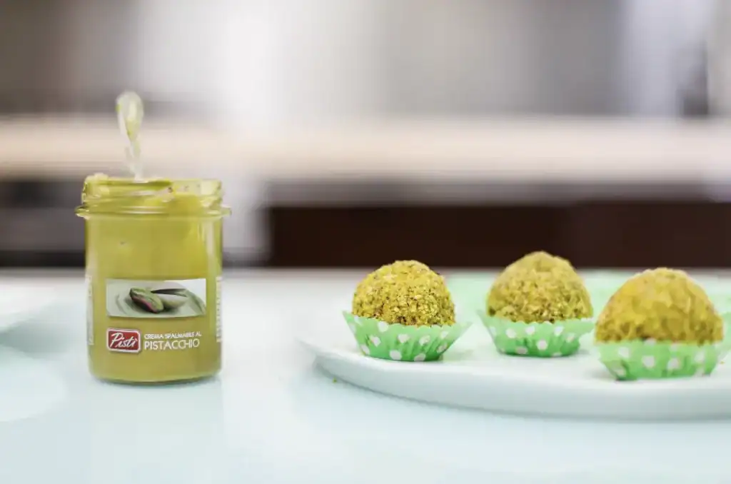 Pistachio Spread and Truffles Pistachio spread jar with pistachio truffles on a white plate.