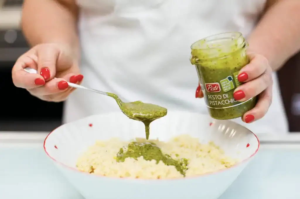 Pesto di pistacchi artigianale Artisanal pistachio pesto being spooned over a dish.