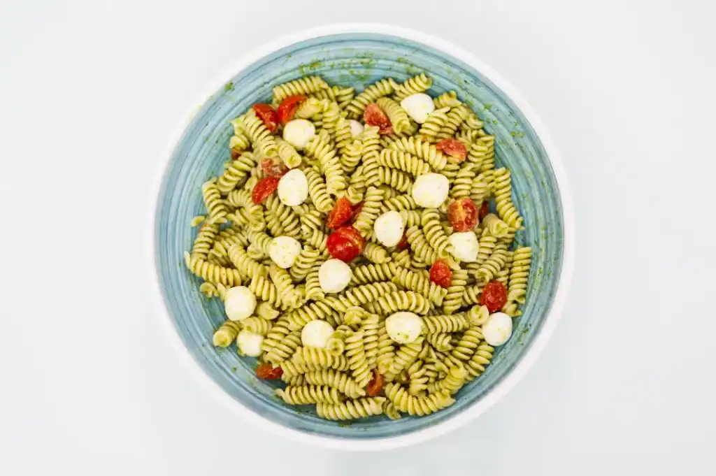 Pasta salad with cherry tomatoes and mozzarella balls Fusilli pasta salad with cherry tomatoes and mozzarella, served in a blue bowl.