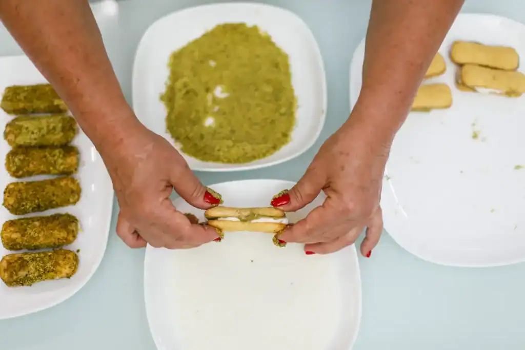 Fritters preparation process Hands preparing Sicilian fritters with filling and breadcrumbs.