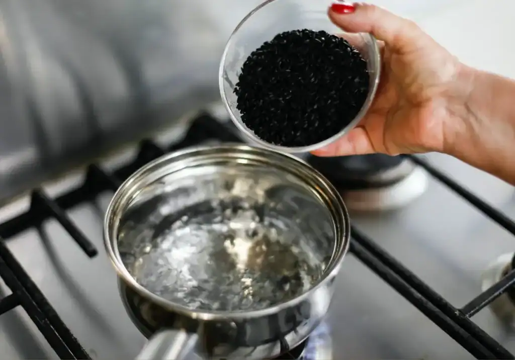 Violet Black Rice Black rice being poured into boiling water on stove.