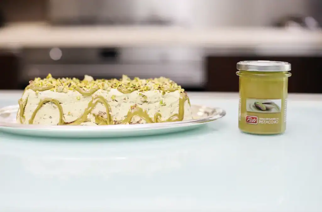 Torta di pistacchio e crema Pistachio and cream cake with pistachio topping on a white plate.