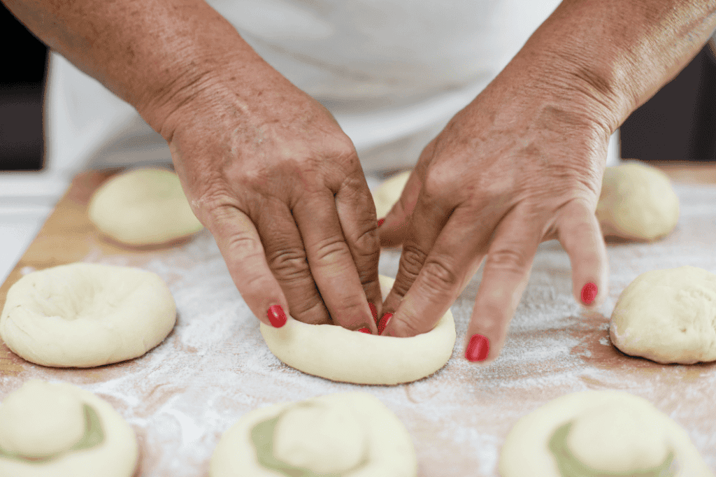 Fatto a mano pasta di mandorle Hand shaping almond paste on a floured surface with small dough balls around.