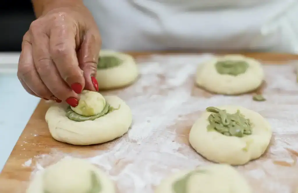 Frolla con ripieno di pistacchio Pistachio-filled pastry being prepared by hand.