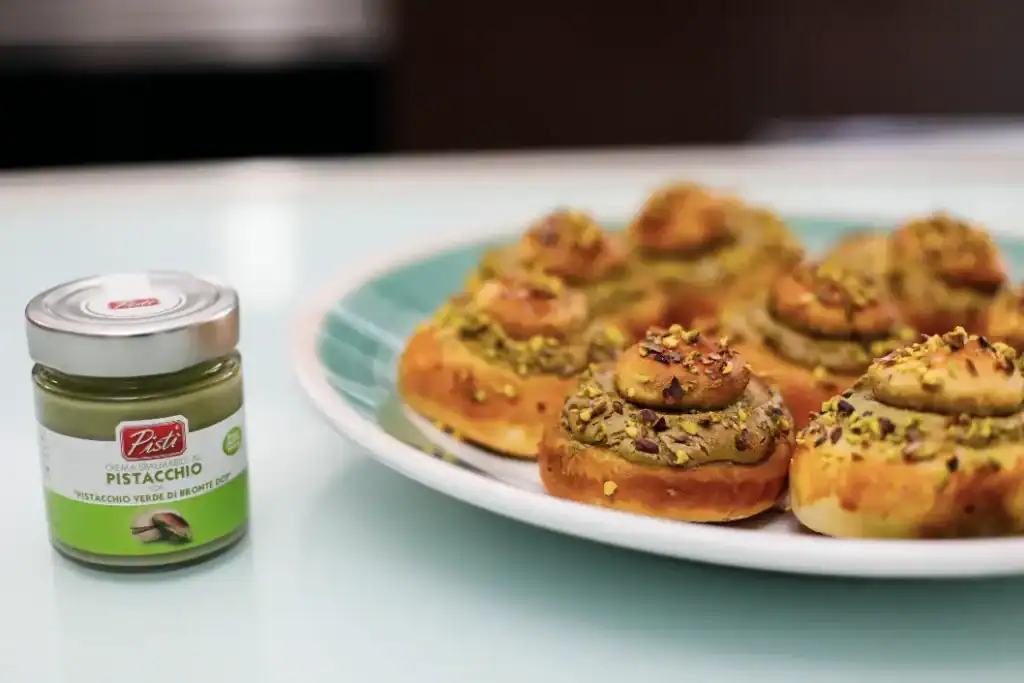 Pistachio Sicilian Pastries Assorted Sicilian pistachio pastries on a white plate with pistachio spread jar nearby.