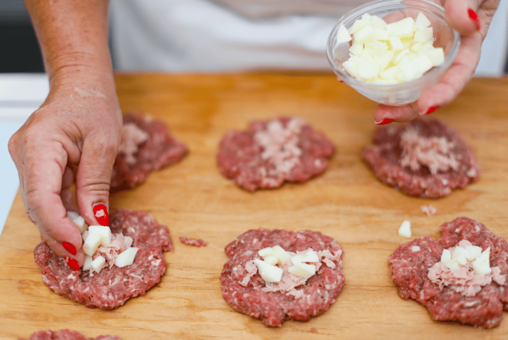 Pistì Sicilian Meat Patties with White Chocolate Preparing Sicilian meat patties with white chocolate on a wooden board.