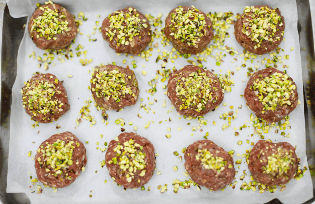 Sweet Pistachio Cookies Pistachio-coated artisanal cookies on baking sheet.