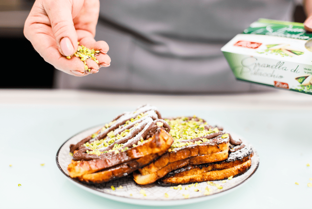 Fette di pane con granella di pistacchio Pistacchio granella being sprinkled on toasted bread slices.