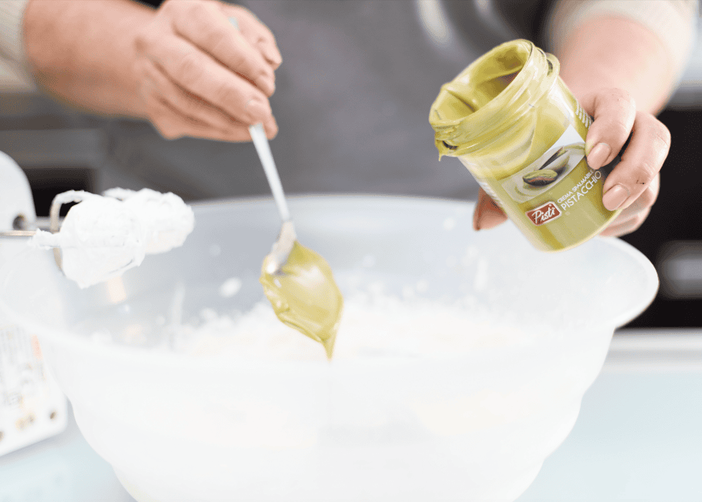 Creamy pistachio spread for desserts and snacks. Delicious pistachio cream being scooped from a jar into a bowl.