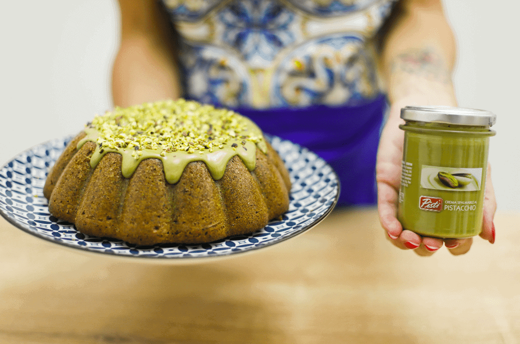 Woman holding a pistachio bundt cake and pistachio cream jar, close-up shot.
