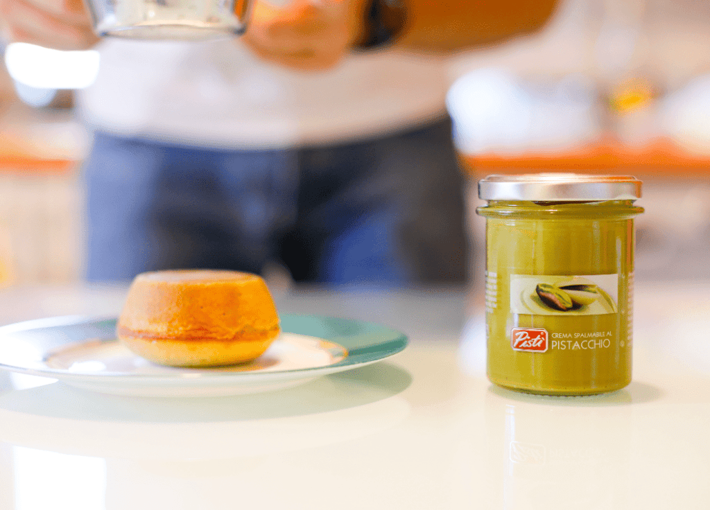 Pistì Pistachio Cream with Cake Pistì pistachio cream jar with cake on a plate, Sicilian artisanal dessert.