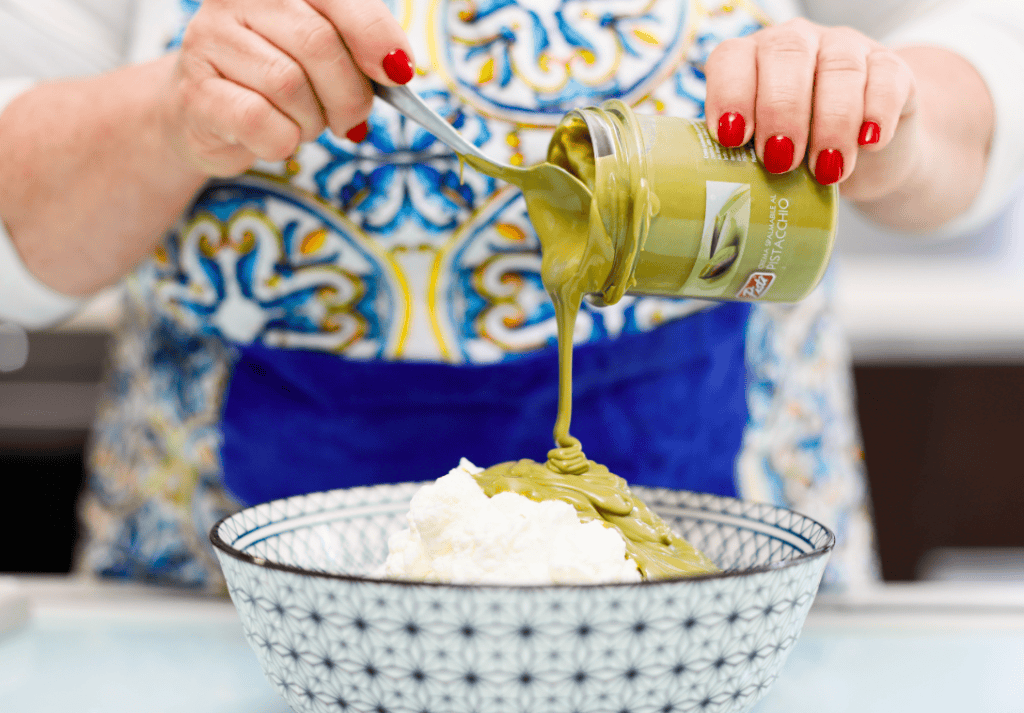 Pistì Green Pistachio Spread Green pistachio spread being poured over ice cream in a bowl.