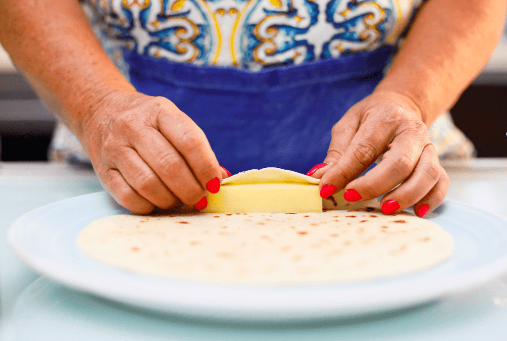 Pistì artisanal Sicilian sweets preparation Woman rolling dough for Sicilian pastry with hands and red nails.