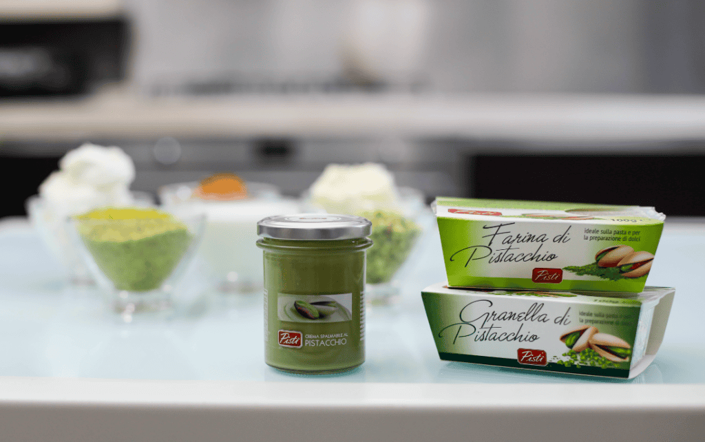 Crema di Pistacchio e Farina di Pistacchio Pistachio cream jar with pistachio flour boxes on a kitchen counter.