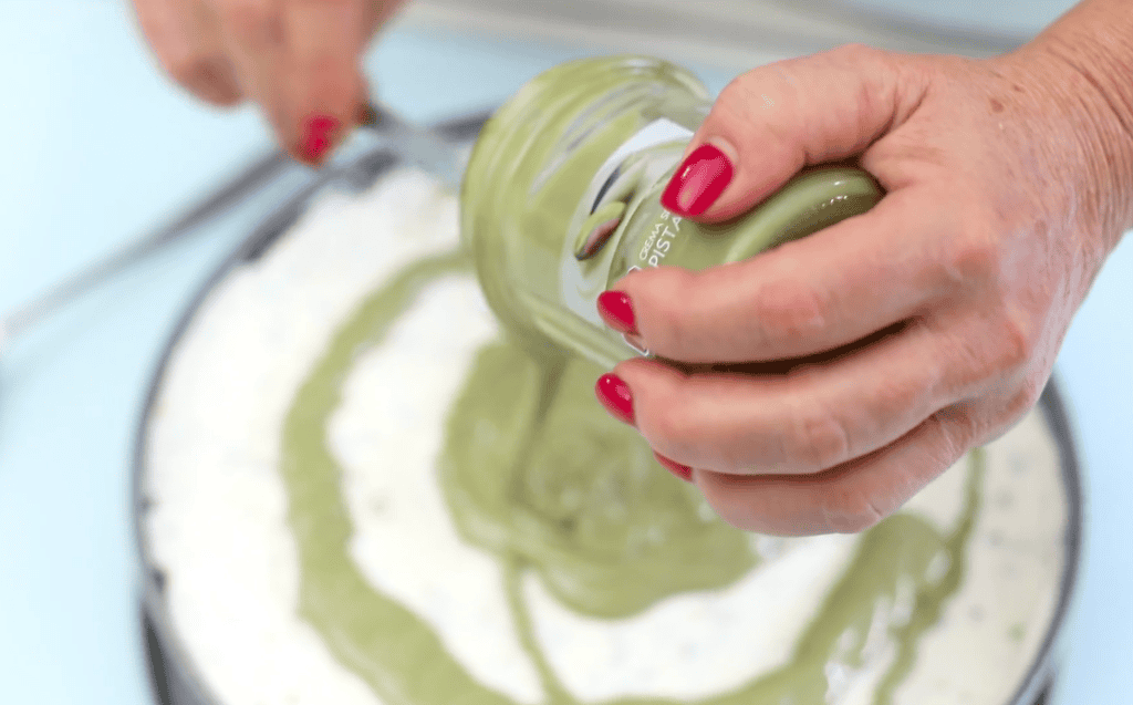 Creamy pistachio spread being poured into a bowl. Hand pouring pistachio spread into a bowl for dessert.
