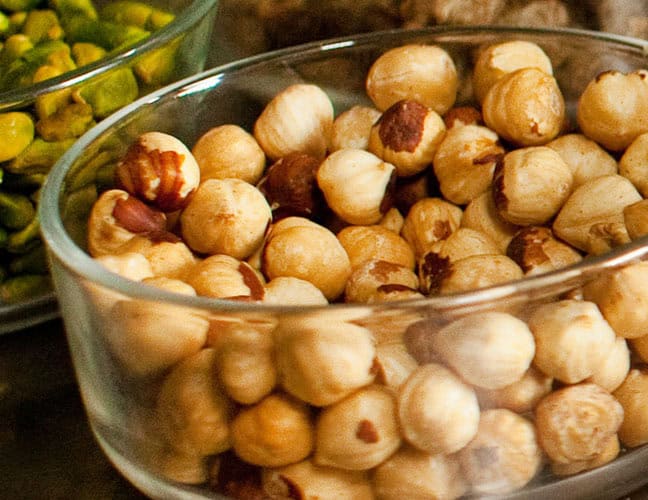 Pistachio nuts in a glass bowl, close-up view.