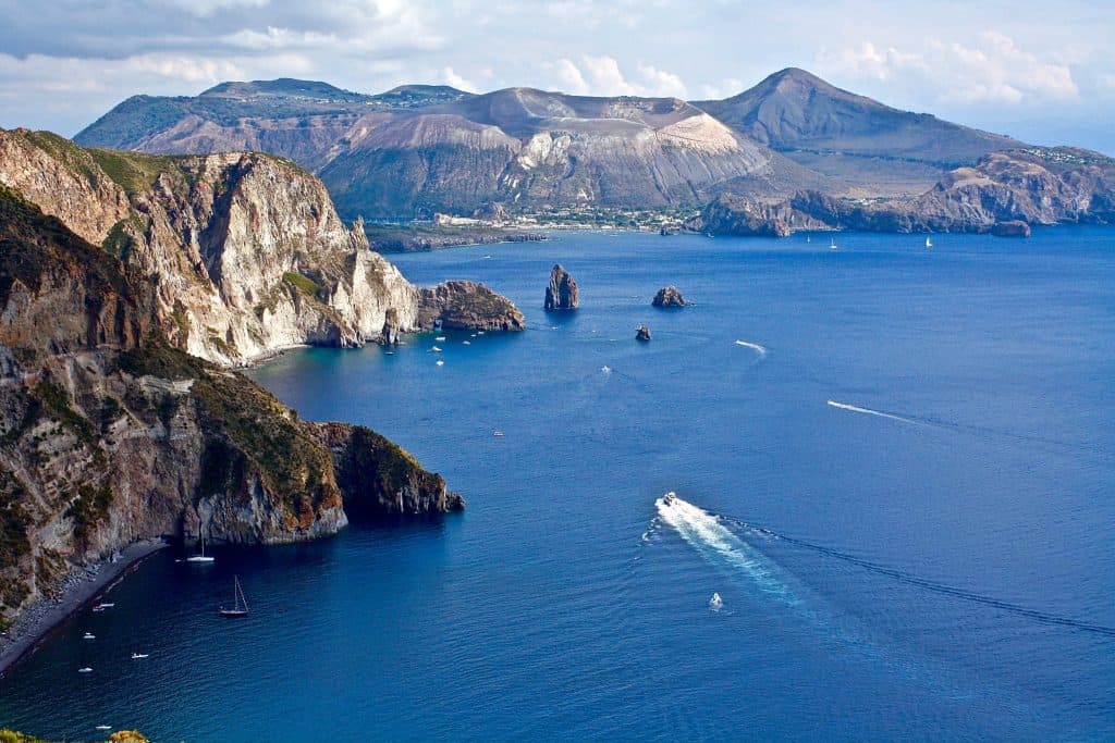 Vasta vista della costa siciliana con scogli e mare blu intenso.