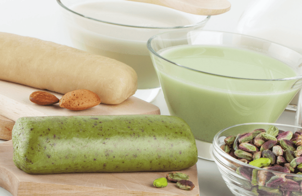 Pistachio cream with pistachios and ingredients on a wooden board.