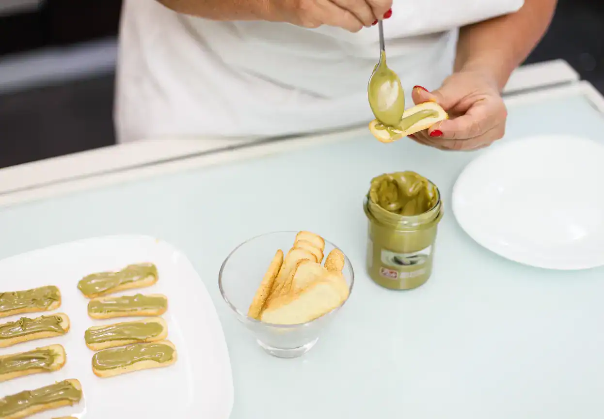 Hand scooping green candied lemon peels from jar, Sicilian artisanal sweets.