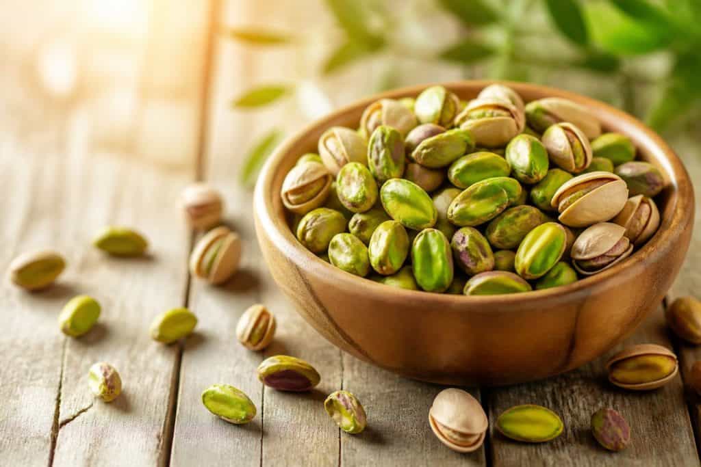 Pistì Sicilian pistachio grains in a wooden bowl on a rustic table.