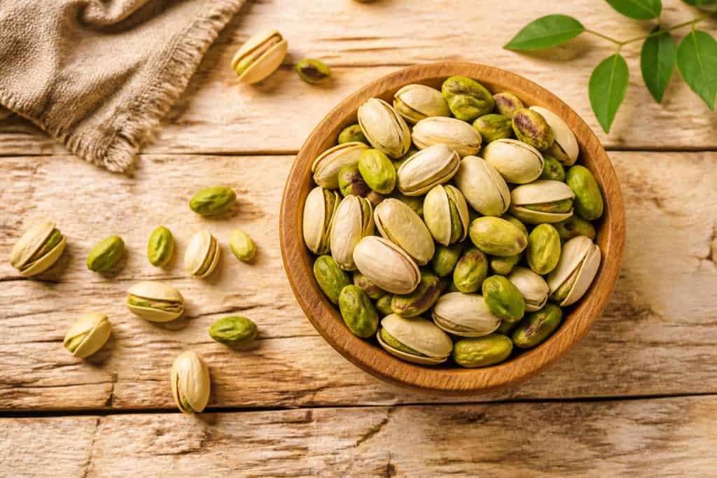 Pistì Sicilian pistachio grains in a wooden bowl on a rustic table.