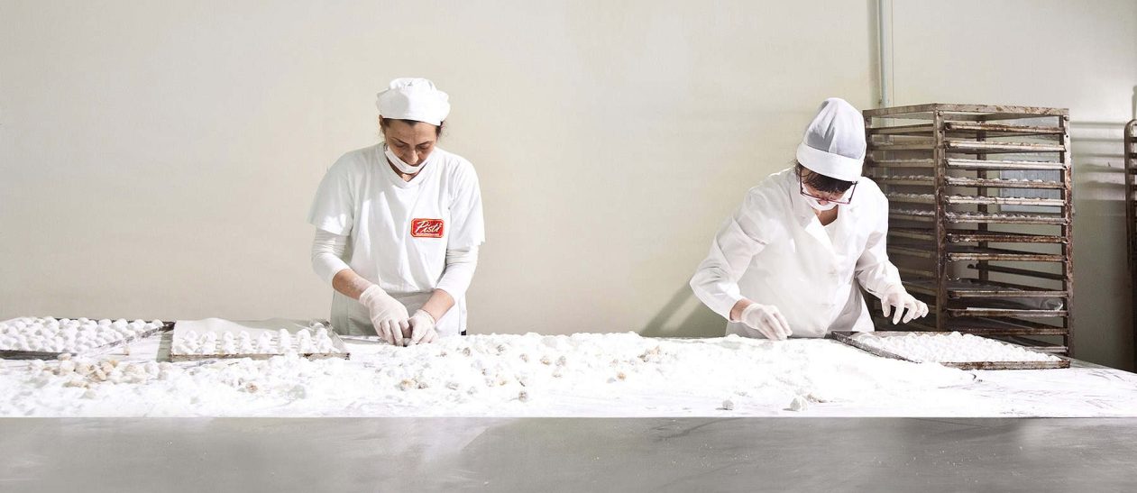 Artisans preparing traditional Sicilian sweets by hand in a clean, professional kitchen.