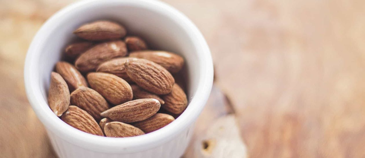 Pistachio nuts in a white ramekin, close-up shot.